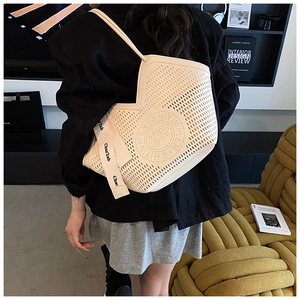 Détail du motif ajouré et de la bandoulière griffée sur le sac cabas beige