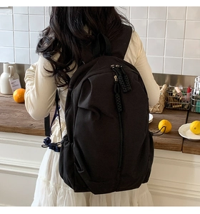 Close-up of black multi-pocket backpack showing woven rope zippers and thick shoulder straps