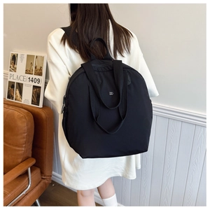 Detail of lightweight black puffy backpack with dual handle and white logo on high-density fabric