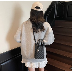 Vue détaillée d'un sac seau tressé noir avec une texture fine et une fine bandoulière