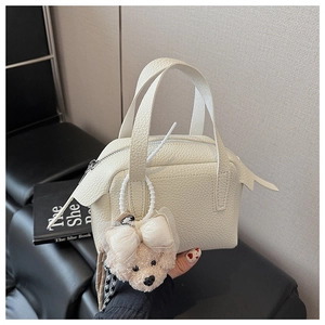 Détail du sac à main en cuir grainé blanc cassé avec un adorable pendentif ours en peluche