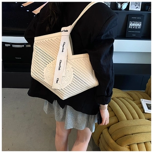 Détail du sac cabas beige ajouré avec motifs perforés et bandoulière en toile élégante