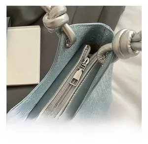 Close-up of sparkling light blue denim bag with silver hardware and knotted handle