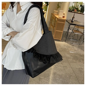 Detail of black patchwork tote with lace ruffle edge and stylish wide shoulder strap