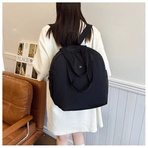 Rear view of model wearing black waterproof nylon backpack with silver logo and dual straps