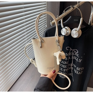 Detail of cream white leather bucket bag with elephant charm and decorative base text