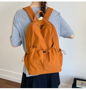 Detail of caramel nylon backpack featuring drawstring pockets and high-density fabric