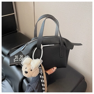 Détail d'un mini sac à main en cuir noir grainé avec un petit pendentif ours peluche