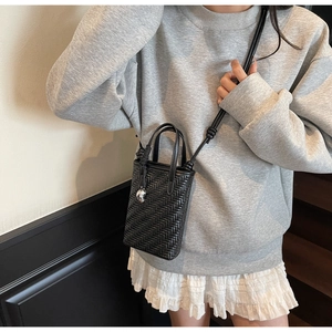 Détail d'un mini sac seau tressé noir avec un pendentif crâne et une bandoulière nouée