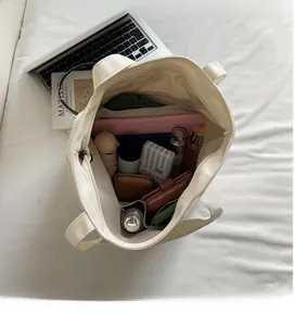 Detailed interior of a white canvas tote bag showing large capacity for laptops and daily items