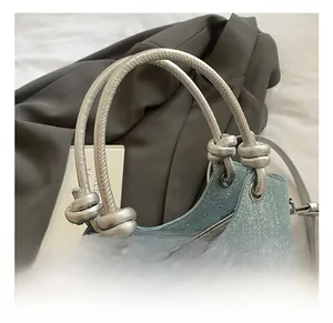 Close-up of blue denim bucket bag with silver knotted handles and star charm