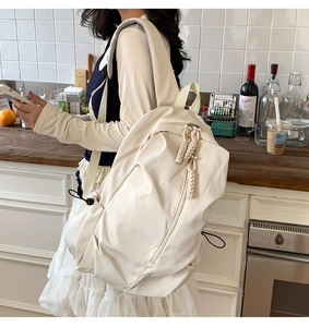 Detail view of large cream leisure backpack with woven rope zipper and side drawstring cords