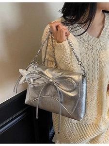 Sac bandoulière argenté métallisé avec nœud et chaîne porté par un mannequin