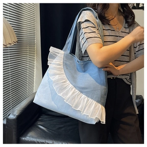 Detailed view of light blue denim tote bag with white lace trim and spacious interior