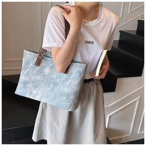 Detail shot of light blue marble textured tote bag with brown leather straps for commuting
