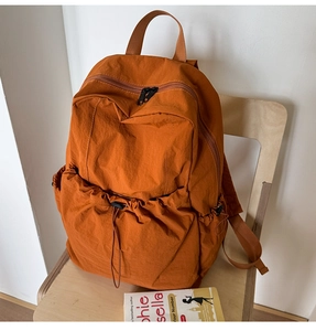 Caramel nylon backpack on wooden chair featuring drawstring pockets and water-resistant texture