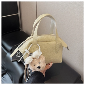 Détail du mini sac à main en cuir jaune pâle avec un pendentif d'ours en peluche mignon