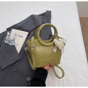 Detail of avocado green crocodile pattern handbag with pearl lace heart pendant and strap