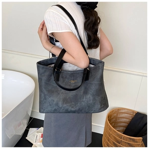 Detail showing the large grey suede tote bag with fashion lettering and long shoulder strap