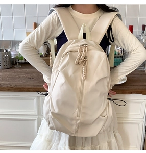 Close-up of a large beige backpack showing side drawstring pockets and padded straps