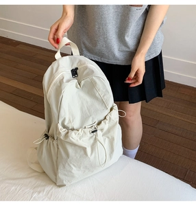 Detail of cream nylon backpack with adjustable drawstring pockets and zipper design