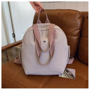 Detail of macaron purple-gray waterproof nylon backpack with silver logo on leather sofa