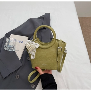 Detail of green faux leather bucket bag with crocodile pattern and pearl heart charm