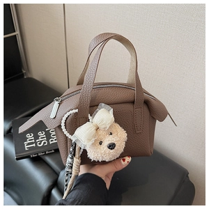 Détail d'un sac à main en cuir marron grainé avec un charmant pendentif chien en peluche
