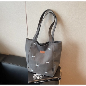 Close-up of embroidered canvas tote bag with dog patterns and brown leather logo patch