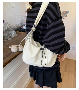 Detail of creamy white drawstring pleated crossbody bag with wide shoulder strap