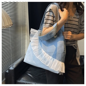 Detailed view of light blue denim tote bag with white lace ruffle edges on model