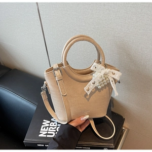 Detail of apricot crocodile texture bag with lace bow and pearl charm accents