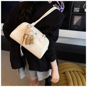 Gros plan sac à épaule en cuir blanc brillant avec pendentif ours et détail de gland