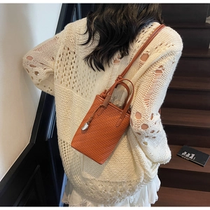 Détail du tissage sur petit sac seau orange-brun avec pendentif en métal argenté