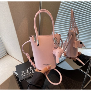 Detail view of pink bucket bag featuring elephant charm and elegant leather texture