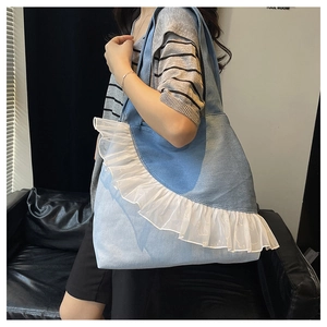 Lifestyle shot of large denim tote bag with lace trim details on a leather sofa