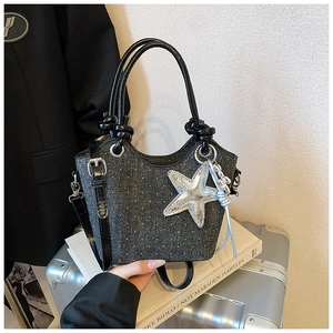 Detail of black denim bucket bag with sparkling rhinestones and silver star charm