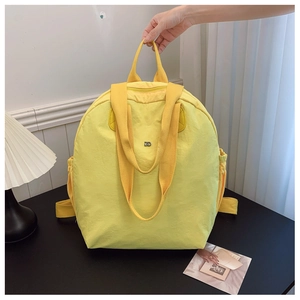 Detailed view of yellow waterproof backpack handle and metallic logo on nylon fabric