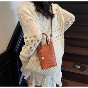 Détail du tissage sur le sac seau marron caramel avec breloque cœur en argent