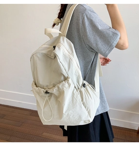 Side view of minimalist cream nylon backpack with adjustable drawstring side pocket