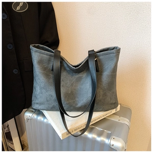 Detail view of large dark grey tote bag with soft texture on a silver suitcase