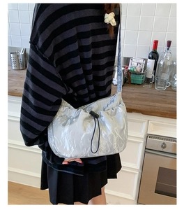 Detail view of the silver metallic pleated dumpling bag showing the adjustable drawstring