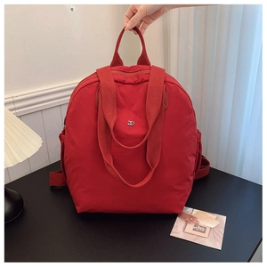 Detail of red waterproof nylon backpack showing top handle and side storage pocket