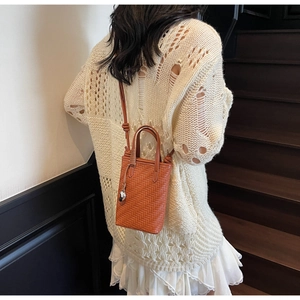 Détail de la texture tissée orange et du motif en V sur ce sac à main élégant