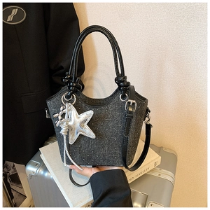 Detailed macro view of black glitter bucket bag with silver star and balloon dog charm