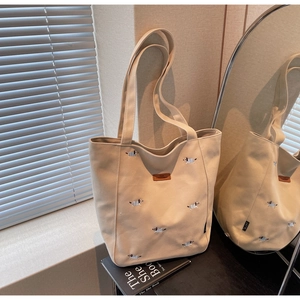 Detail of beige canvas tote bag with dachshund embroidery and brown leather patch