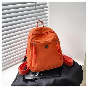 Vue détaillée d'un mini sac à dos en nylon orange vif avec plusieurs poches zippées
