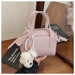 Détail d'un sac à main rose en cuir PU grainé avec un petit pendentif de chien en peluche