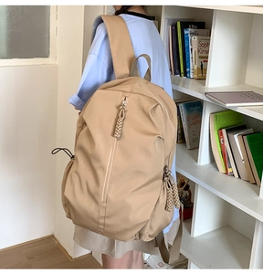 Side view of khaki nylon backpack on a model showing wide padded straps and side pockets
