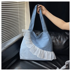 Detailed view of light blue denim tote bag with elegant white organza ruffle trim detail